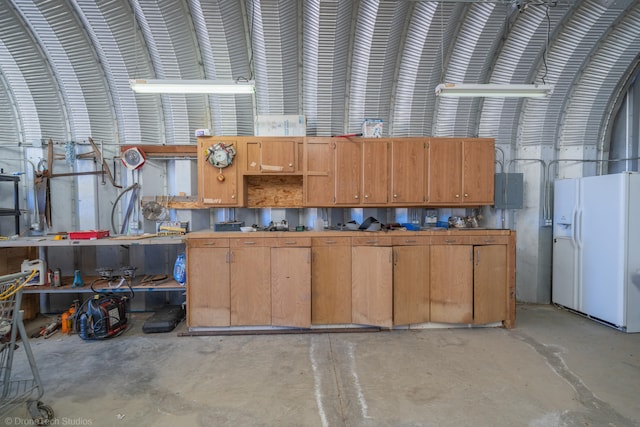 interior space with a workshop area, white fridge with ice dispenser, and electric panel