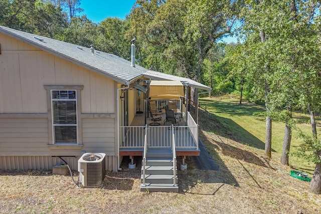 rear view of house featuring a lawn, cooling unit, and a wooden deck