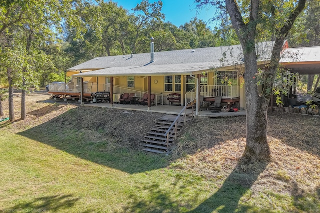 back of house with a deck, a lawn, and a patio area