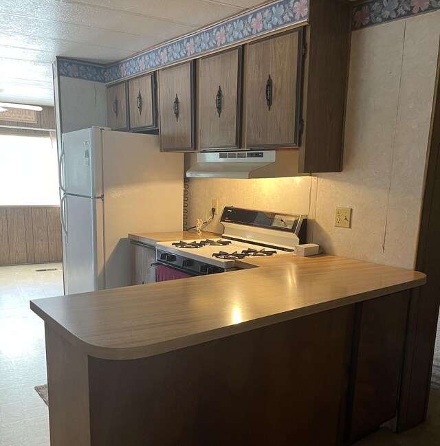 kitchen featuring kitchen peninsula, white refrigerator, and range