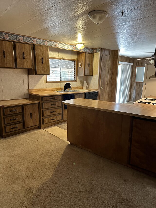 kitchen featuring wood walls, white refrigerator, sink, black dishwasher, and light colored carpet