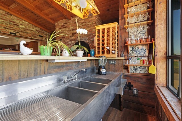 kitchen with wooden ceiling, dark wood-type flooring, brick wall, and vaulted ceiling with beams