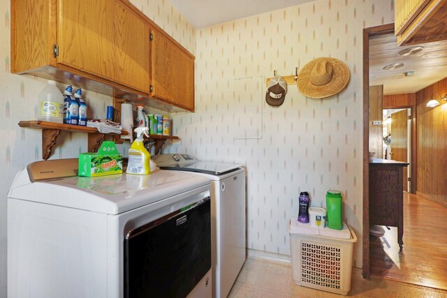 washroom with washing machine and dryer, cabinets, and light wood-type flooring