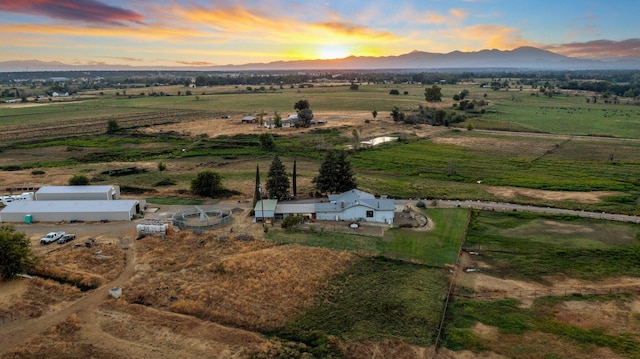 aerial view at dusk featuring a mountain view and a rural view