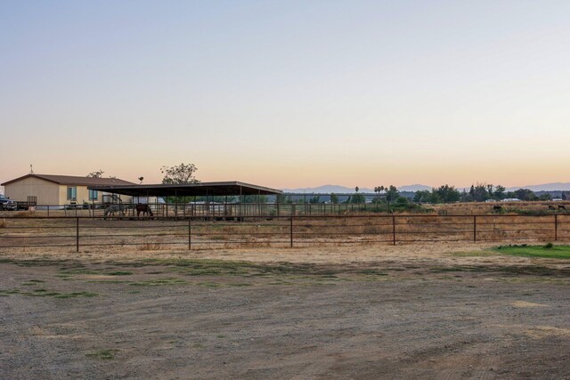 yard at dusk featuring a rural view