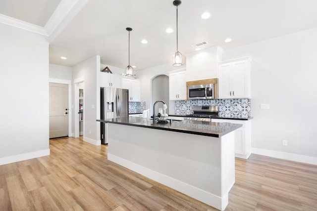 kitchen with a center island with sink, light hardwood / wood-style flooring, pendant lighting, appliances with stainless steel finishes, and white cabinets