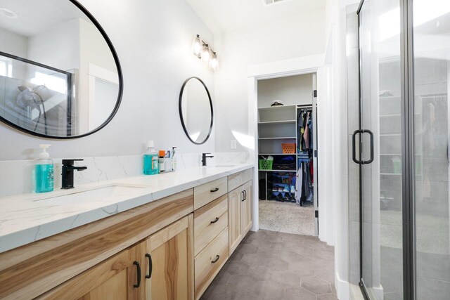 bathroom featuring tile patterned flooring, vanity, and a shower with shower door