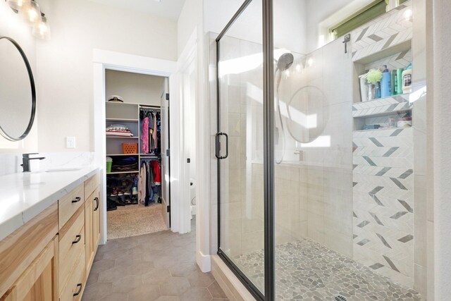 bathroom featuring tile patterned floors, a shower with shower door, and vanity