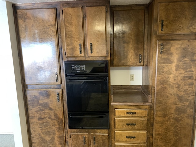 kitchen with a warming drawer, dark countertops, and dobule oven black