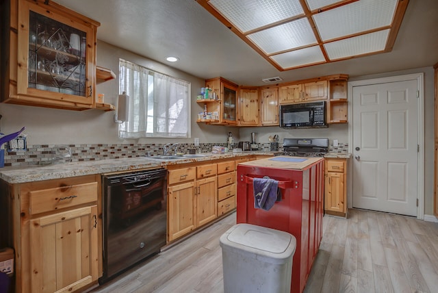 kitchen with tasteful backsplash, black appliances, a center island, sink, and light hardwood / wood-style floors