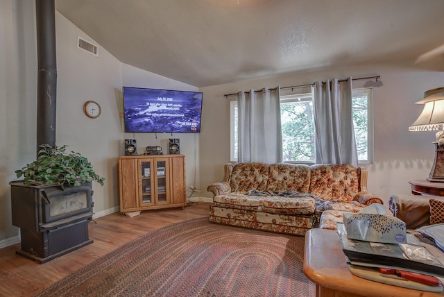 living room with lofted ceiling, wood-type flooring, and a wood stove