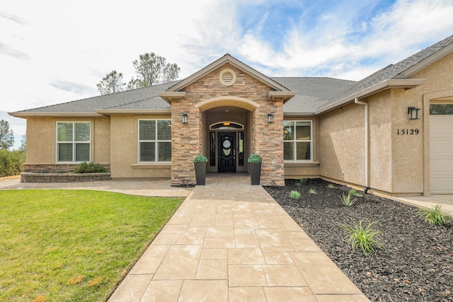 view of exterior entry with a yard and a garage