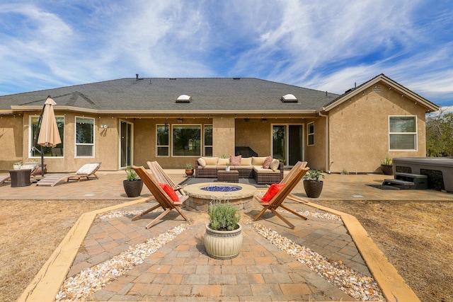 rear view of property with a hot tub, an outdoor living space with a fire pit, and a patio