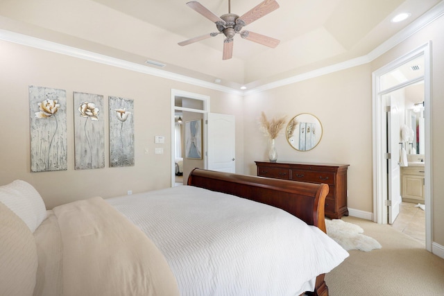 carpeted bedroom with ornamental molding, ceiling fan, a tray ceiling, and ensuite bath