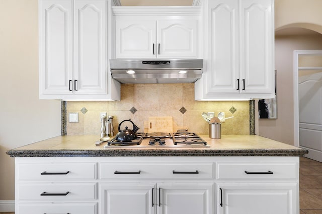 kitchen with extractor fan, white cabinets, stainless steel gas stovetop, and backsplash