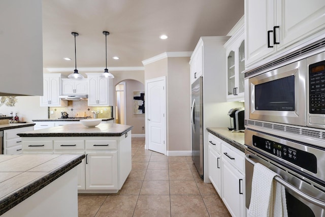 kitchen featuring appliances with stainless steel finishes, pendant lighting, white cabinets, ornamental molding, and light tile patterned floors