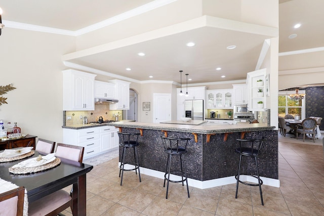 kitchen with white cabinets, stainless steel appliances, light tile patterned floors, and a breakfast bar area