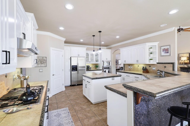 kitchen featuring a center island, kitchen peninsula, white cabinetry, decorative light fixtures, and built in appliances