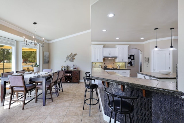 dining room with crown molding, light tile patterned flooring, and a notable chandelier