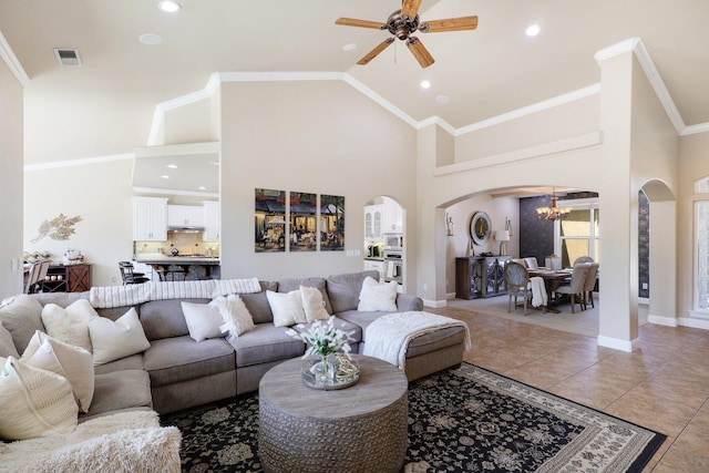 living room with high vaulted ceiling, ornamental molding, tile patterned flooring, and ceiling fan with notable chandelier