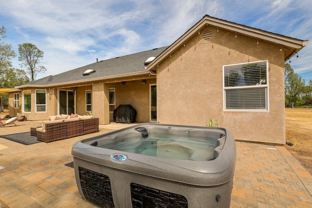 back of property with a hot tub, outdoor lounge area, and a patio