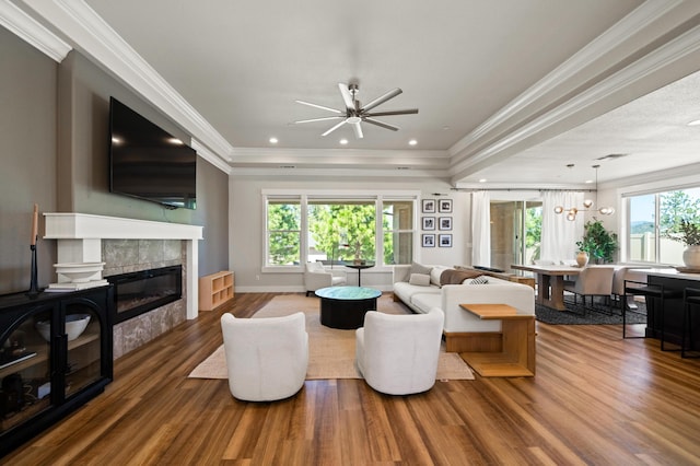 living room featuring crown molding, wood-type flooring, a tile fireplace, and ceiling fan