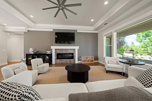 living room featuring ceiling fan, a raised ceiling, light hardwood / wood-style floors, and ornamental molding