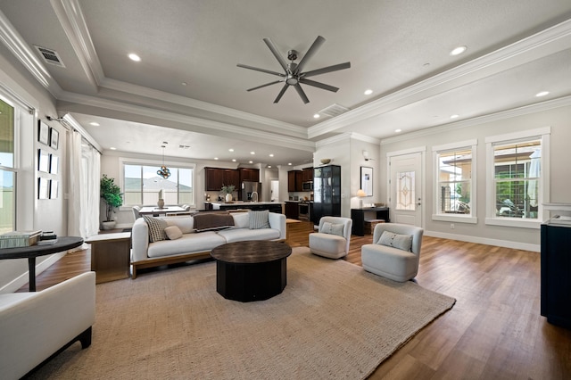 living room with ornamental molding, hardwood / wood-style flooring, a healthy amount of sunlight, and ceiling fan