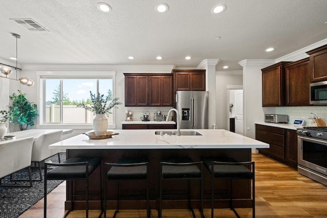 kitchen featuring light wood-type flooring, a kitchen island with sink, stainless steel appliances, and sink