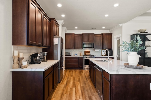 kitchen with stainless steel appliances, light hardwood / wood-style floors, sink, decorative backsplash, and ornamental molding