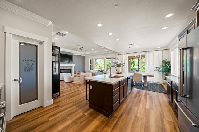 kitchen featuring a center island with sink, stainless steel appliances, hardwood / wood-style floors, and dark brown cabinets