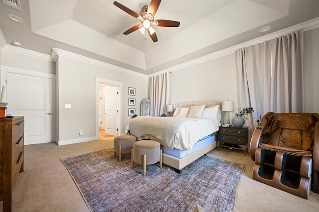 carpeted bedroom featuring a tray ceiling, connected bathroom, crown molding, and ceiling fan