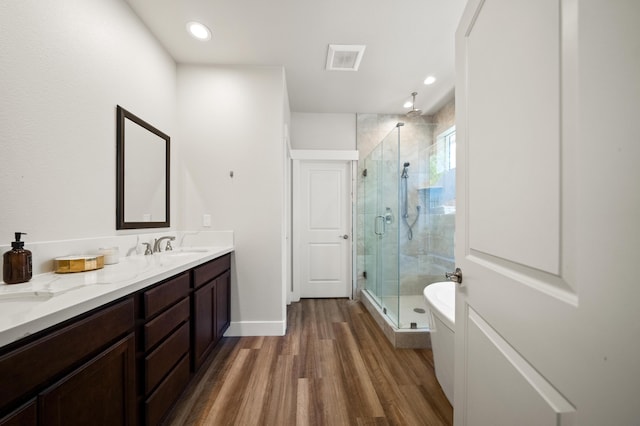 bathroom featuring vanity, hardwood / wood-style floors, and plus walk in shower