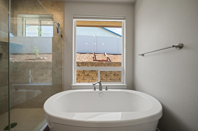 bathroom featuring a wealth of natural light and shower with separate bathtub