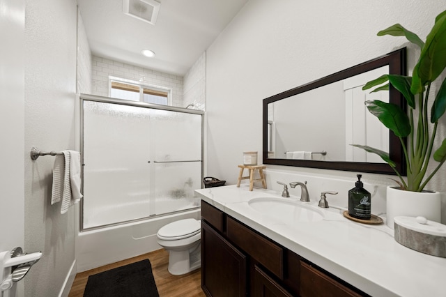 full bathroom featuring shower / bath combination with glass door, vanity, toilet, and wood-type flooring