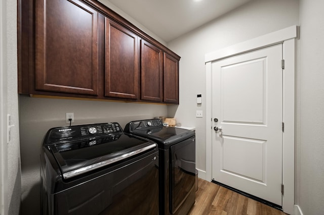 clothes washing area featuring cabinets, washer and clothes dryer, and light wood-type flooring