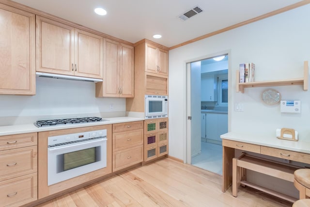 kitchen featuring light brown cabinets, visible vents, and white appliances