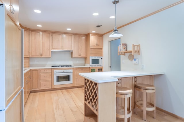 kitchen with light wood-type flooring, white oven, light brown cabinetry, and kitchen peninsula