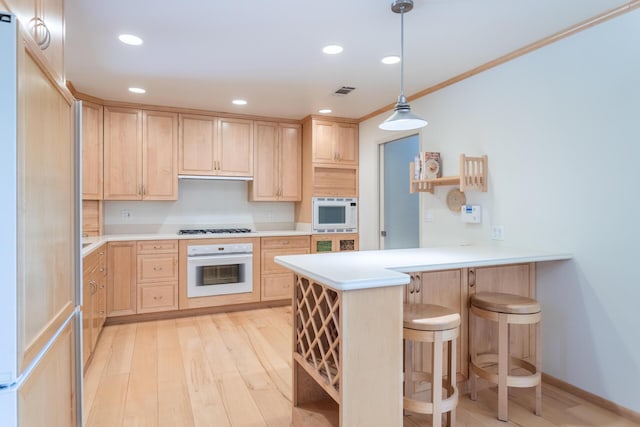 kitchen featuring white appliances, light brown cabinets, light wood-type flooring, and a peninsula