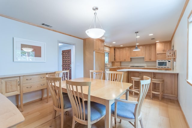 dining area with light hardwood / wood-style flooring, ornamental molding, and sink