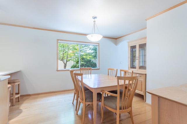 dining space with ornamental molding and light hardwood / wood-style floors