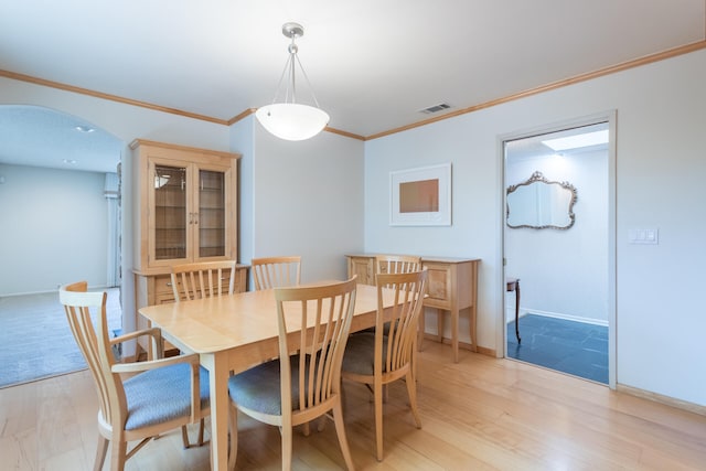 dining space with ornamental molding and light wood-type flooring