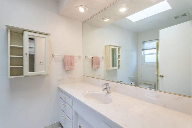 bathroom featuring vanity, toilet, and a skylight