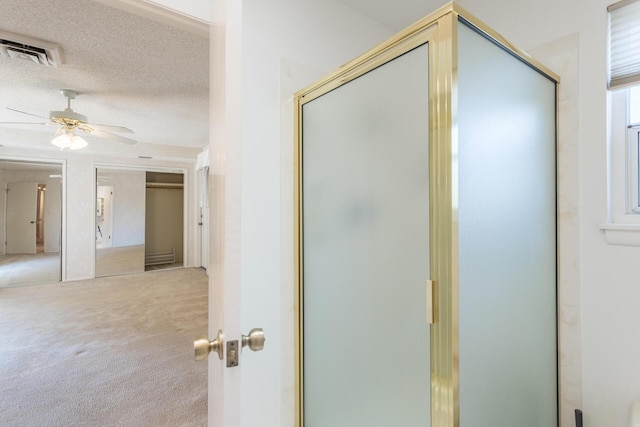 bathroom featuring visible vents, a shower stall, a textured ceiling, and a ceiling fan