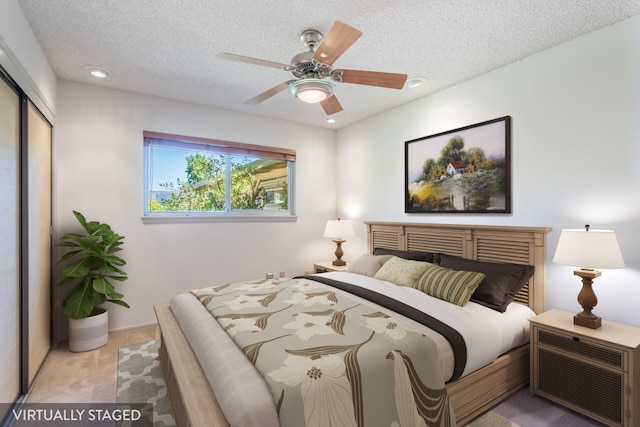 bedroom with a closet, ceiling fan, light colored carpet, and a textured ceiling