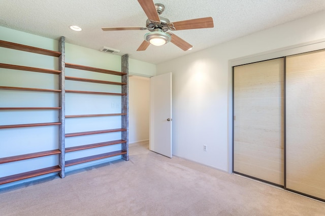 unfurnished bedroom with visible vents, ceiling fan, carpet flooring, a closet, and a textured ceiling