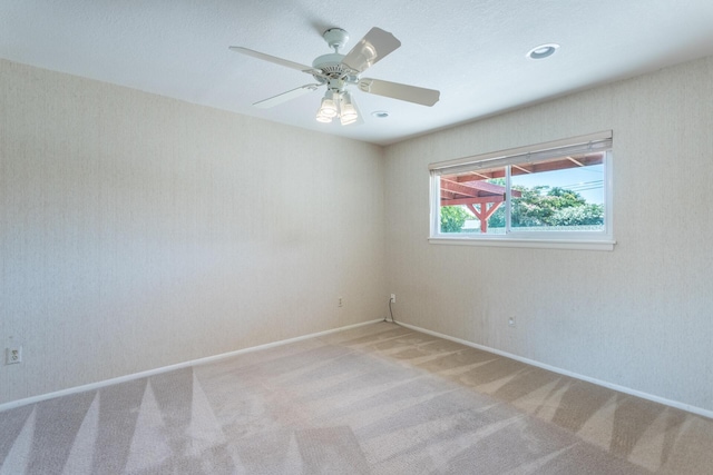 empty room featuring a ceiling fan, carpet, and baseboards