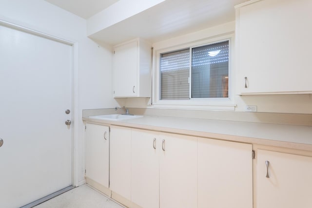 kitchen with light countertops, white cabinets, and a sink