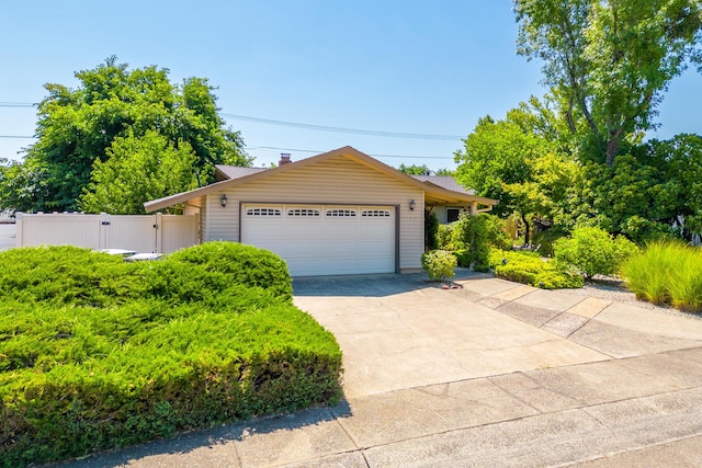 ranch-style home featuring driveway, fence, an attached garage, and a gate