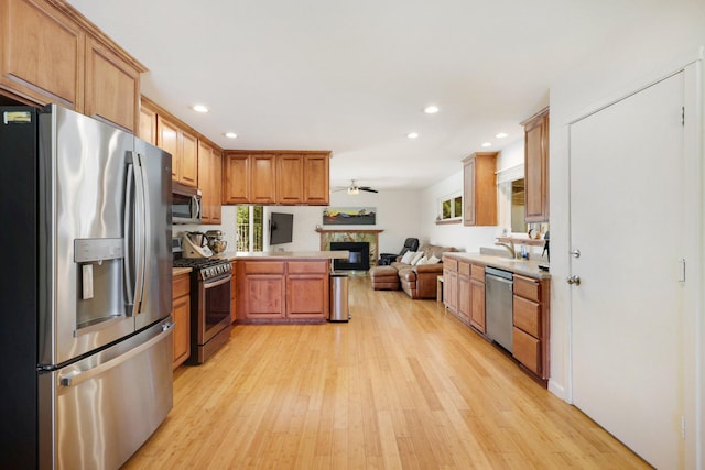 kitchen featuring appliances with stainless steel finishes, a healthy amount of sunlight, kitchen peninsula, and light hardwood / wood-style floors